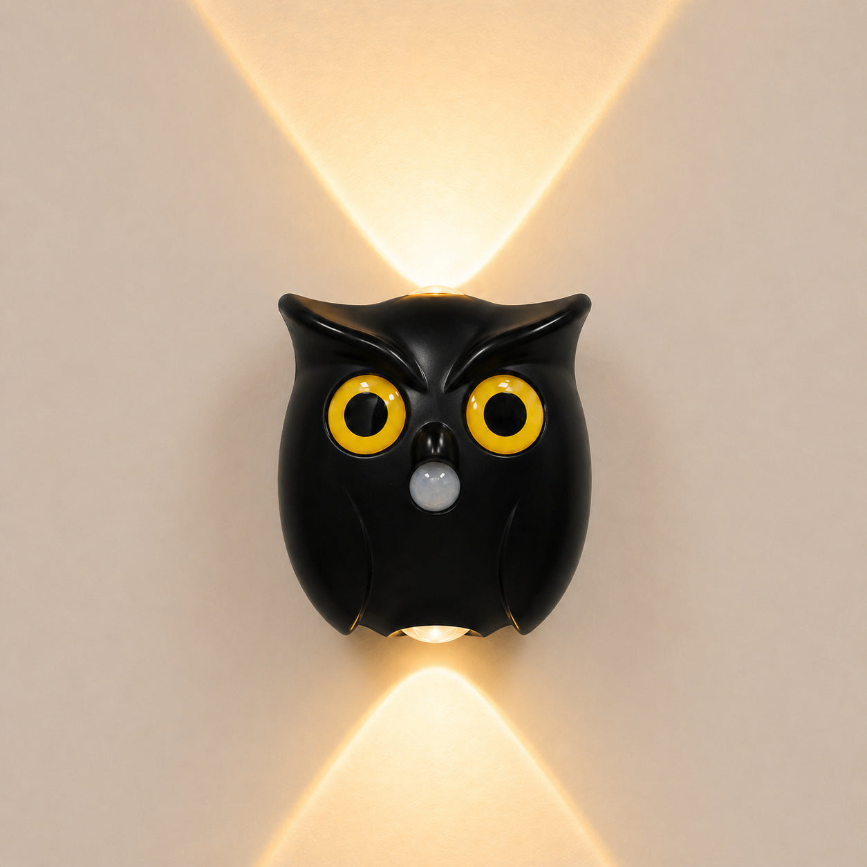 Owl LED night light in black casting a warm up and down glow