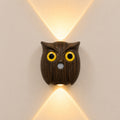 Nordic owl motion-sensor wall light in dark wood finish glowing warm on a wall